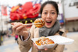 © PR Image Factory - selective focus of delicious takoyaki octopus ball held on chopsticks by an amazed Asian Japanese woman and shown to camera in Shinsekai area in Osaka Japan