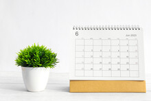 June 2023 Desktop Calendar For Planners And Reminders On Wooden Table With Plant Pots On A White Background.