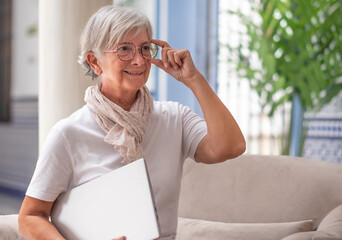 Smiling senior woman in office holding laptop under her arm