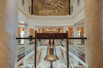 Art Deco stucco grand atrium, lobby or foyer with dramatic staircase or stairs on luxury cruiseship or cruise ship ocean liner railing or hand rails, carpets, elevators and flower deco