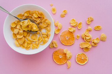 Wall Mural - top view of dried oranges near bowl with corn flakes and organic milk on pink.