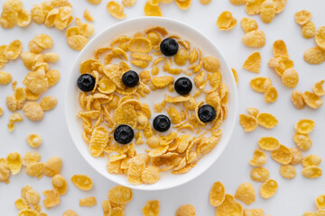 Wall Mural - top view of tasty corn flakes in bowl with organic milk and fresh blueberries isolated on white.