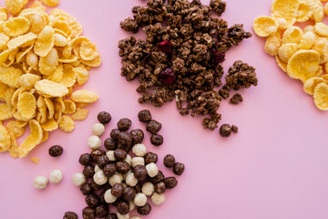 Sticker - top view of corn flakes near cereal balls with vanilla and chocolate flavors and tasty granola isolated on pink.