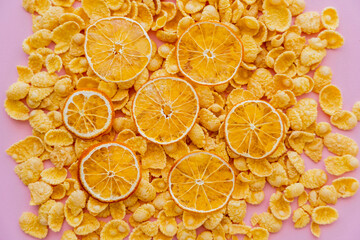 Sticker - top view of dried oranges on top of crispy breakfast corn flakes isolated on pink.