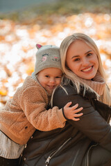 Wall Mural - Happy mother and daughter are walking in the autumn park. Beautiful family in warm clothes. Fall.