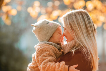 Wall Mural - Happy mother and daughter are walking in the autumn park. Beautiful family in warm clothes. Fall.