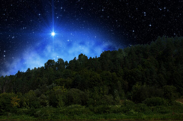 birth of new star in the starry night sky beyond the mountains covered with forest. star of jesus ch