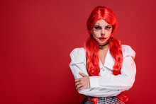 Offended Woman With Bright Ponytails And Clown Makeup Standing With Crossed Arms Isolated On Red.