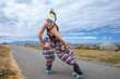 © Mat Hayward - Asian woman smiling and having fun on roller skates at a waterfront park while wearing a visor, bikini top and puffy pants.