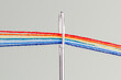 © Minakryn Ruslan  - multi-colored threads for sewing in the form of a rainbow pass through an antique needle on a white background