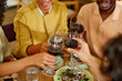 A Group of friends toasts with red wine in a restaurant at the dinner table.