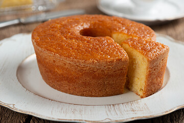 Homemade round cornmeal cake, typical Brazilian foodmade from corn in a June party and dish on a rustic wooden table with one slice