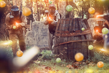 Wall Mural - Teams of friends facing on battlefield in outdoor paintball arena, image with glowing and blur effects