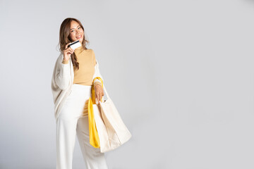 Smiling fashionable in warm sweater with shopping bags showing credit card and smiling to camera.