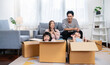 © paulaphoto - Asian family father mother daughter girl packing cardboard box moving, online marketing e-commerce unpacking stuff belongings home delivery. Lifestyle happy white family together relocation