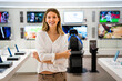 © NDABCREATIVITY - Beautiful young woman choosing which digital device to buy in tech store..