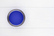open can with blue paint on a white wooden background top view with copy space