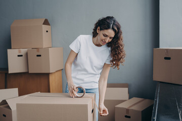 Wall Mural - Delivery service female worker using duct tape packing goods in cardboard box for transportation