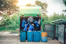 Garbage Transportation Workers. Scavengers Take Bins. Men Load A Metal Container With Garbage Into A Car For Collecting And Transporting Garbage