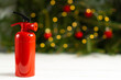 The fire extinguisher stands on a white table, against the background of a Christmas tree decorated with colorful electric garlands, in a home environment. Security concept