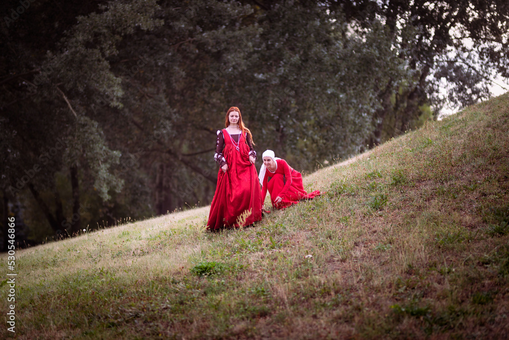 Living history: a 15th-century woman dressed as a rich lady in a Venice-style dress, her maid adjusting the train of her dress