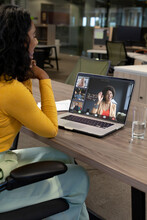 Vertical Of Happy Biracial Businesswoman Making Laptop Video Call With Diverse Colleagues On Screen