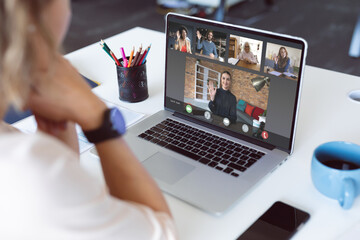 Poster - Caucasian businesswoman at desk making laptop video call with diverse colleagues waving