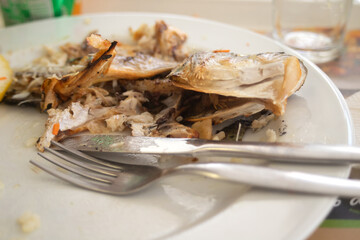 Poster - head and bones of fish on plate with fork and knife