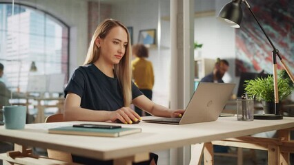 Poster - Beautiful Female in a Black Casual Dress Sitting at a Desk in Creative Office, Working on Tasks on Laptop Computer. Young Creative Specialist Writing Corporate Project Plans for Marketing Agenda.