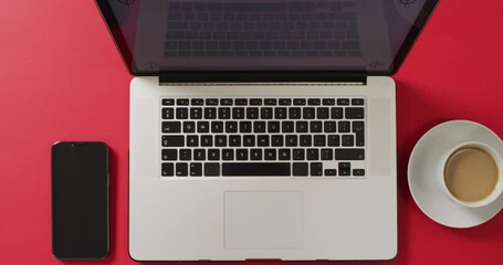 Wall Mural - Overhead view of laptop with smartphone and coffee on red desk