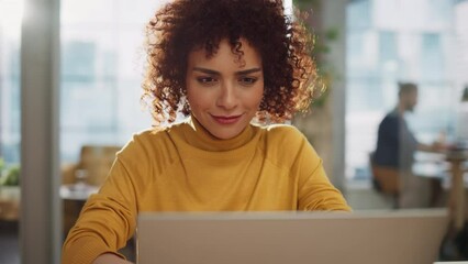 Wall Mural - Close Up Portrait of a Happy Middle Eastern Manager Sitting at a Desk in Creative Office. Young Stylish Female with Curly Hair Using Laptop Computer in Marketing Agency.