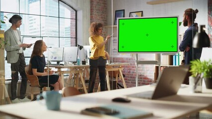 Wall Mural - Positive Businesswoman Leading a Team Meeting in Creative Office Conference Room. Excited Multiethnic Woman Showing Presentation on Green Screen Mock Up Chroma Key Monitor.