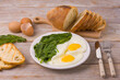 Breakfast on the table with fried eggs and spinach. Closeup view&