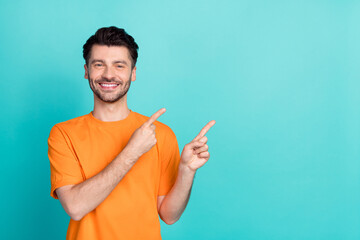 Poster - Portrait photo of young handsome positive confident nice man wear orange t-shirt fingers pointing empty space professional worker isolated on cyan color background