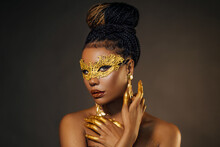 Portrait Sexy African Woman Face Close Up In Golden Venetian Carnival Mask. Girl Fashion Model Perfect Skin, Golden Evening Holiday Makeup, Glitter Diamond Stones Lip Gloss, Hands In Gold Liquid Paint