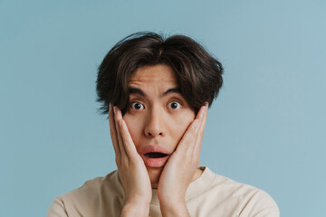 Young asian man wearing t-shirt expressing surprise at camera