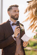 Stylish man with microphone talking speech on wedding day