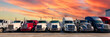Lined up Semi trucks on a parking lot at logistics warehouse with orange sunset sky