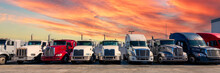 Lined Up Semi Trucks On A Parking Lot At Logistics Warehouse With Orange Sunset Sky