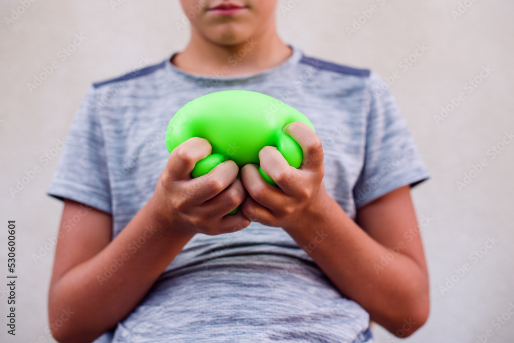 Teen boy playing with anti stress sensory ball squeeze toy. Giant stress balls are soft to