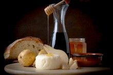 Cheese, Pears, Wine, And Bred On The Board With Honey Spoon Pouring Honey With From A Jar