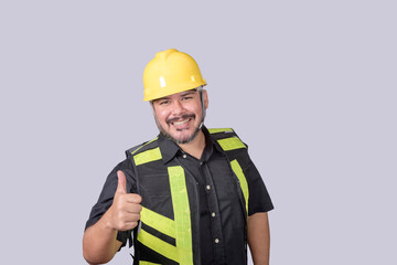 Wall Mural - A burly foreman or engineer wearing a hardhat and safety vest gives a thumbs up of approval. Isolated on a gray background.