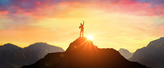 Wall Mural - Man on mountain peak with open arms welcoming new day with sunrise. Success. successful man with hands up on peak of mountain at sunset. Successful person