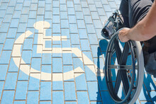 Disabled Person In A Wheelchair Walking Past A Disabled Person Parking Sign