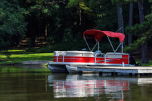 Pontoon Boat At Private Dock On Lake.