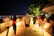 Turista paseando de noche por puente peatonal iluminado rodeado de gente desenfocada por el movimiento. Ciudad de Hue, en Vietnam