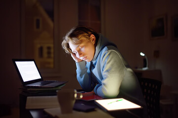 Tired teenager napping while studying at home with laptop and tablet pc at night. Online learning, distance lessons, freelance - modern lifestyle young man working late night at home office