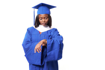 An African-American woman in a blue robe and hat on a white isolated background looks at the watch on her hand. The concept of education, a female graduate student. High quality photo