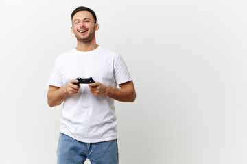 Wall Mural - Happy smiling tanned handsome man in basic t-shirt enjoy favorite game with joystick gamepad posing isolated on over white studio background. Copy space Banner Mockup. Gamer RPG concept