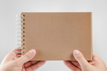 Wall Mural - Notepad in hand. Blank notepad in the hands of a man on a white background. Hands hold a book without text. A man is holding a book with a blank cover.